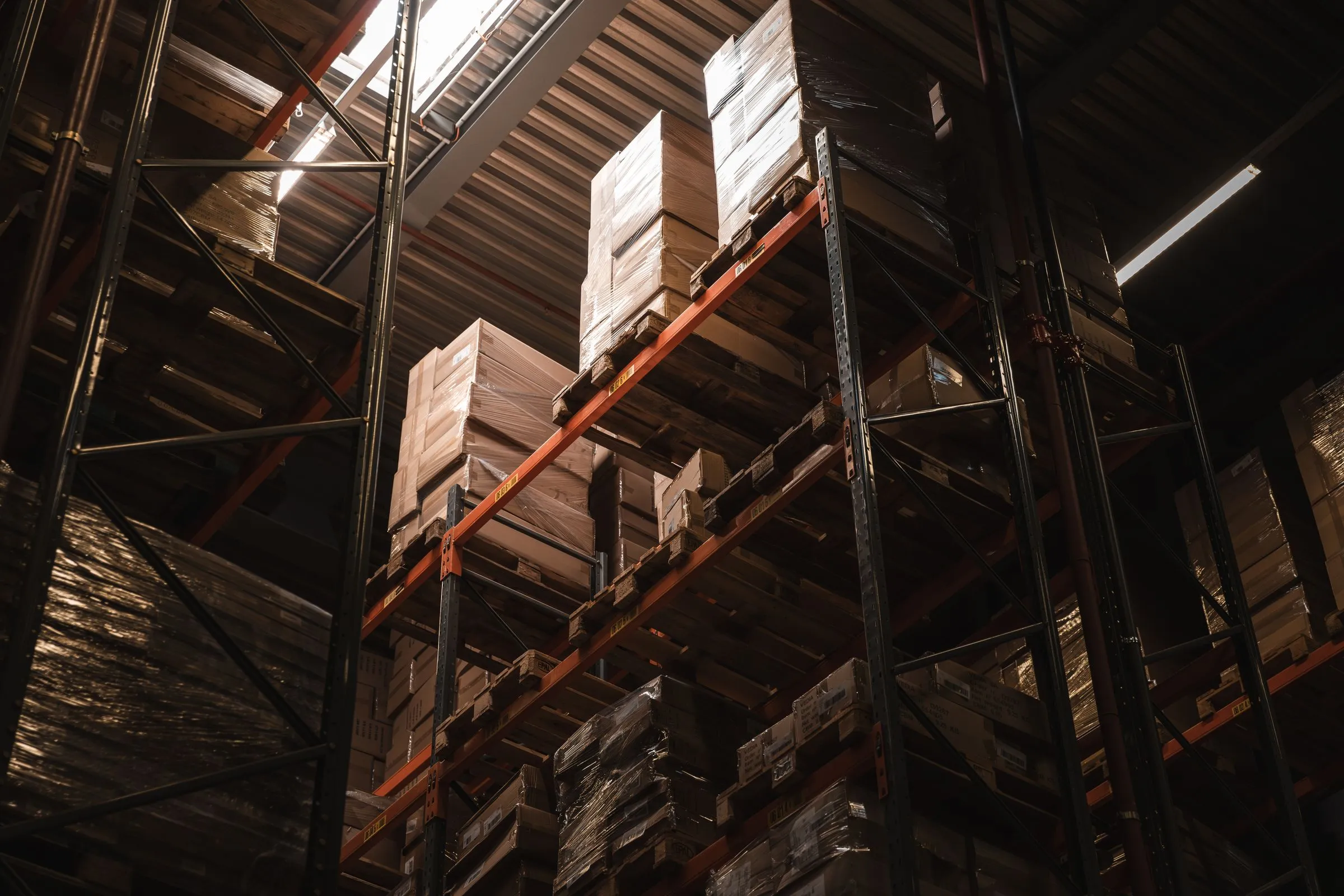 Tall warehouse racking stacked with palletised, wrapped stock